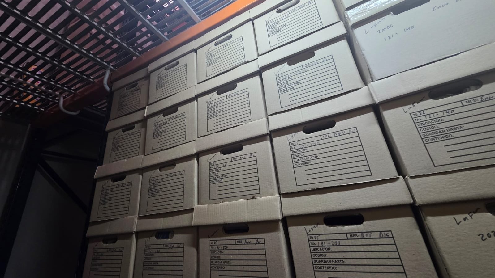 Cajas de archivo rotuladas y ordenadas en una estantería, después de la intervención de SOS Archivos